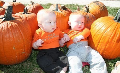 Cute Twins Babies Sitting With Pumpkin