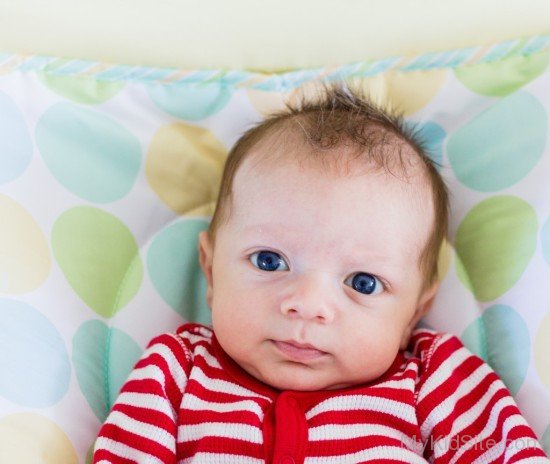 Baby Boy Winkling On White Pillow