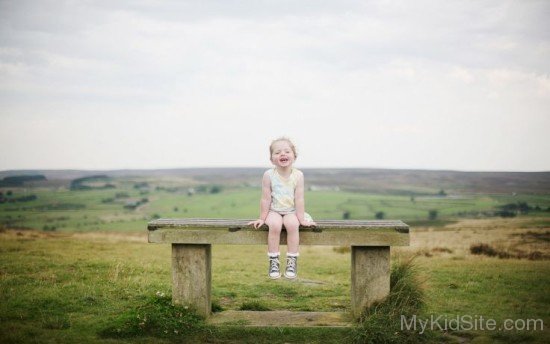 Cute Baby Girl Sitting On Bench